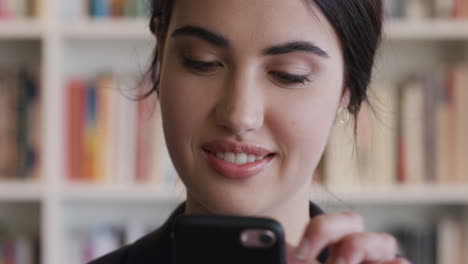 retrato de una hermosa estudiante usando una fuente móvil en la biblioteca