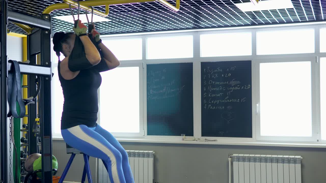 Woman Doing Hanging Leg Raises in Gym