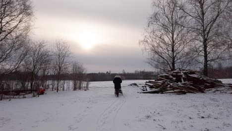 Mutter-Schiebt-Kinderwagen-Auf-Verschneiten-Landschaft-Hof-In-Der-Nähe-Von-Holzstapel