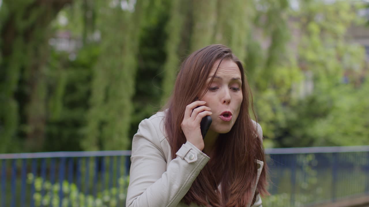 스트레스를 받거나 화를 내고 있는 여성은 생활비, 부채 및 청구서 지불에 대한 재정적 걱정으로 밖에서 휴대 전화로 이야기하고 있습니다.