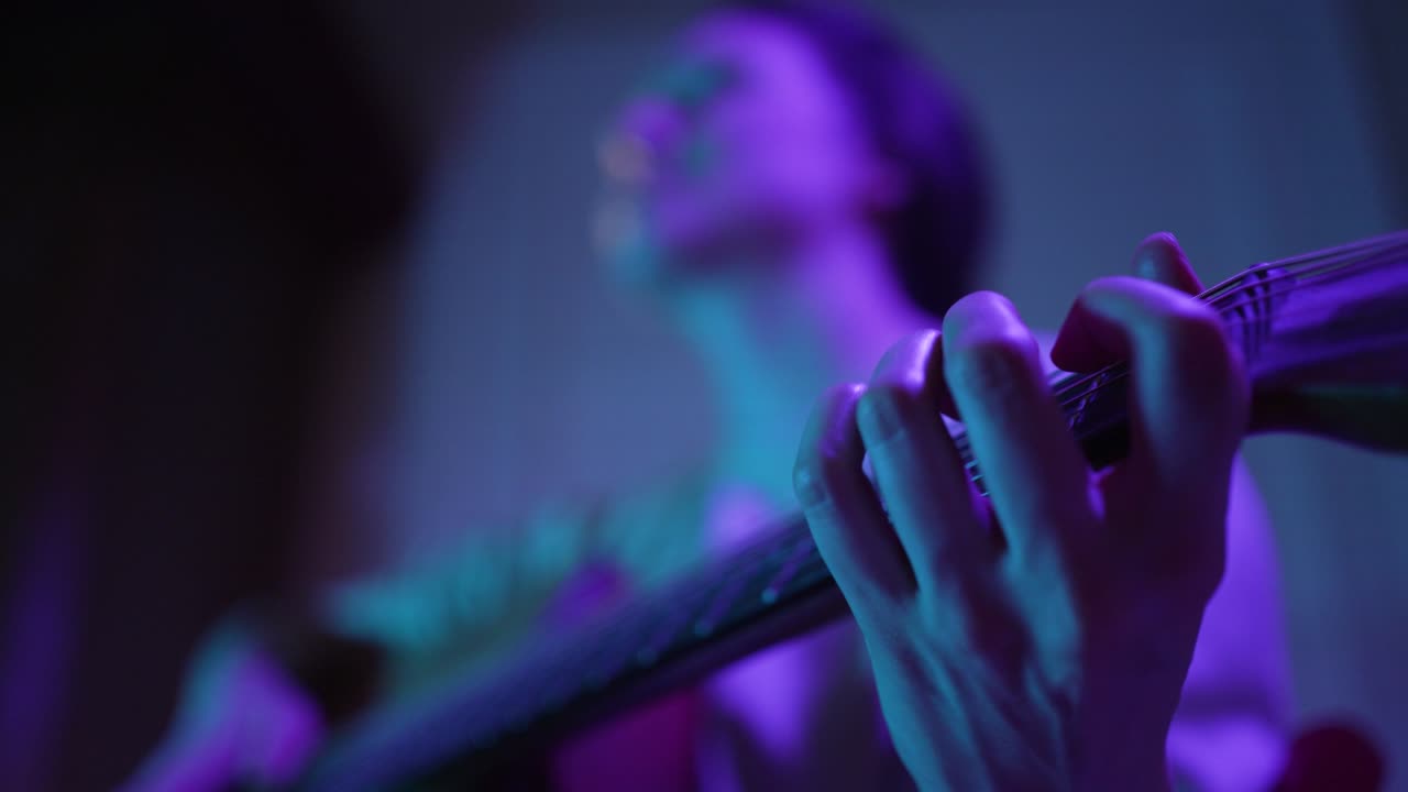 músico toca la guitarra en el escenario iluminado por luz púrpura