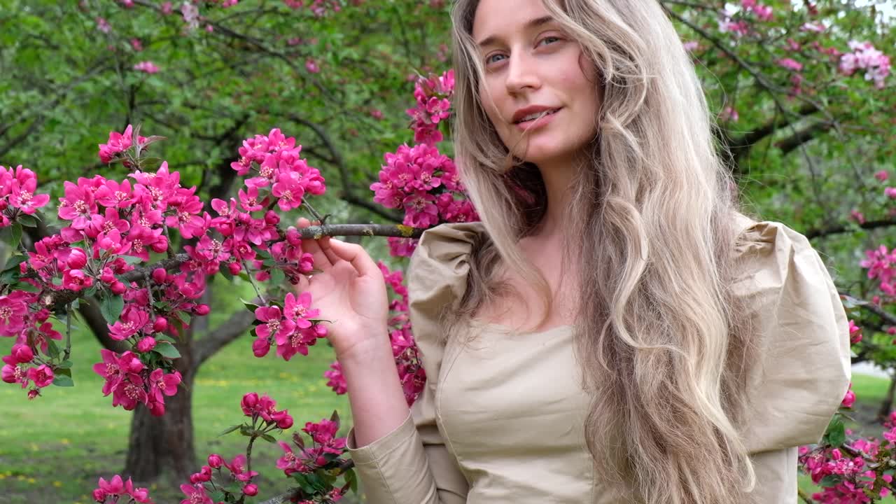 Brunette woman in a brown dress near a blooming tree in a park