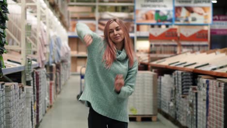 longhaired woman dances in hardware store between the rows