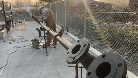 toma cinematográfica de un soldador soldando él mismo un gran tubo de metal