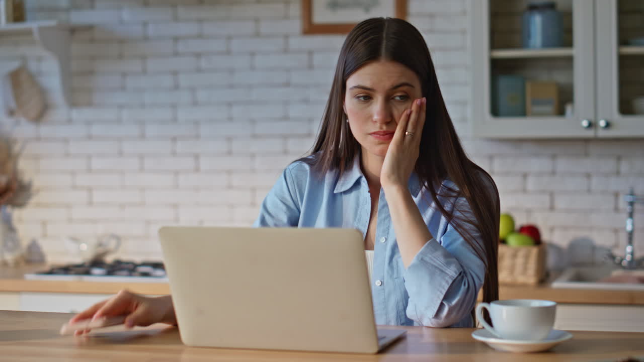 Sad woman taking cellphone from kitchen countertop closeup. Lady closing laptop