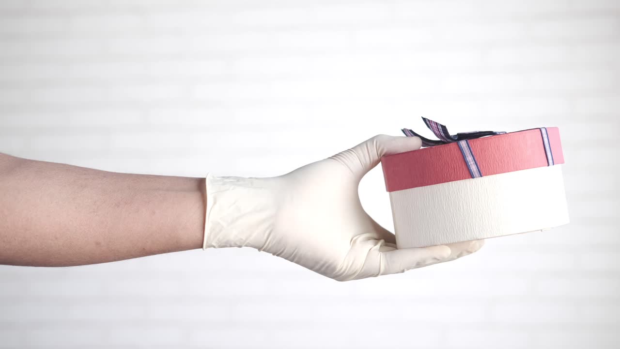 선물 상자를 들고 있는 장갑을 입은 손