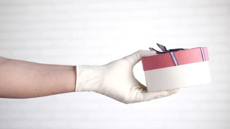 con guantes de mano sosteniendo una caja de regalos