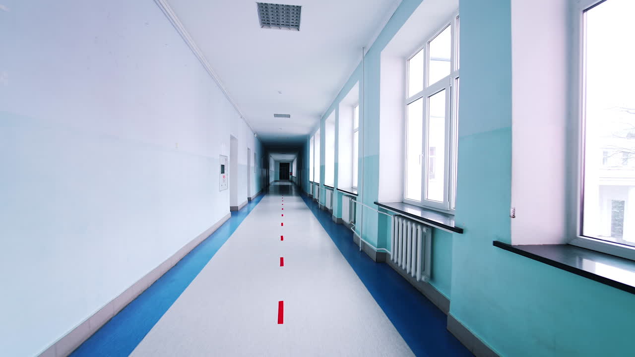 Motion along the corridor inside empty college. Blue long hallway with big windows in modern university.