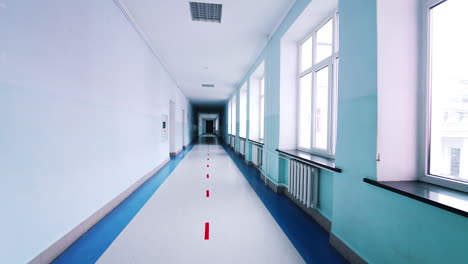 motion along the corridor inside empty college. blue long hallway with big windows in modern university.