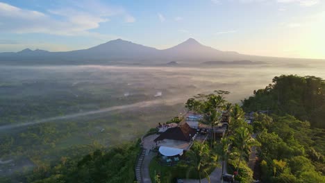 Aerial-view-of-Enam-Langit-Restaurant-on-the-top-of-Menoreh-Hill-in-sunny-morning-and-mountain-range-on-the-horizon