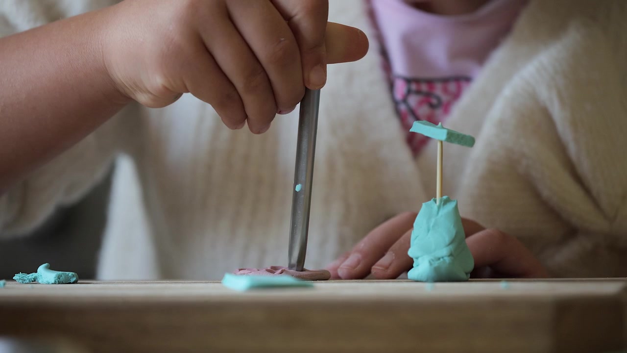 Bambina a un tavolo da lavoro gioca con la plastilina, vista ravvicinata dal basso