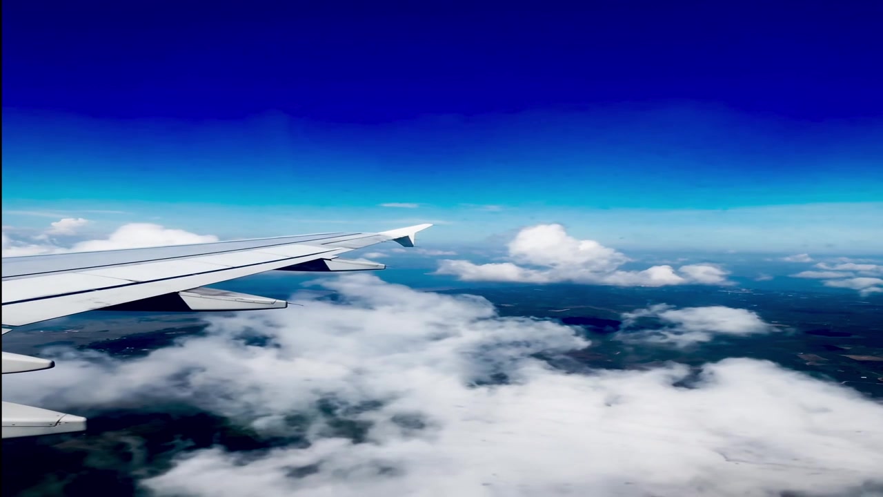 Vista aerea dell'ala di un aereo sopra nuvole e paesaggio