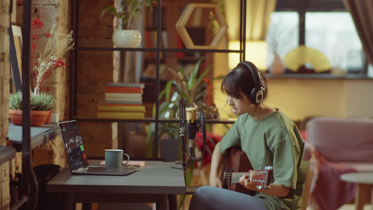 아시아 여성이 집에서 음악을 녹음하고 있습니다.