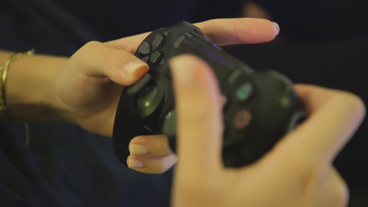 primer plano de manos femeninas usando el controlador dualshock ps4 negro, botones de spam para jugar dentro de casa