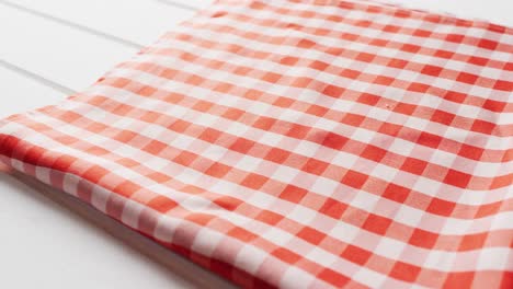 close up of folded red and white checkered blanket on white background with copy space