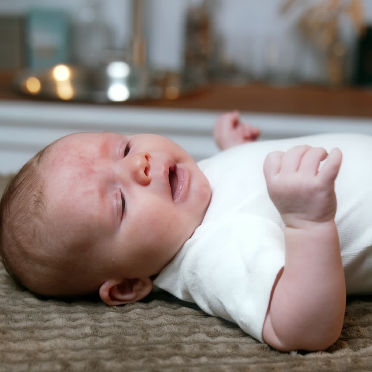 Lovely Caucasian newborn lies on its back yawning. Cute tiny baby boy sneezes adorably. Side view close up