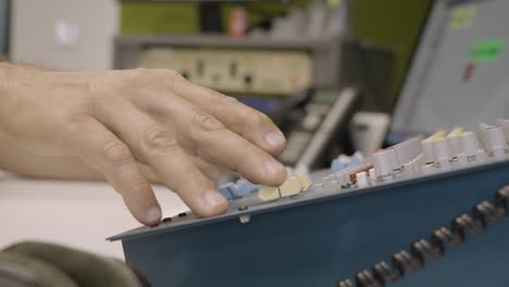 man adjust knob on audio mixing equipment, close up view