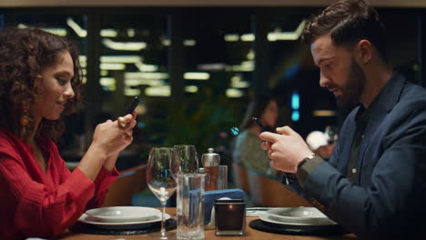 digital couple surfing phone on restaurant dinner date. social media concept.