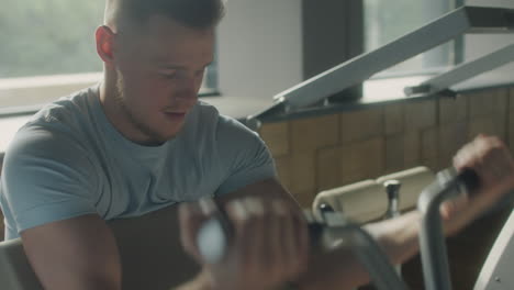 man exercising with preacher curl machine in gym