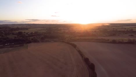 Volando-Lentamente-Hacia-La-Puesta-Del-Sol,-Pasando-Sobre-Campos-Ondulados-Y-Tierras-De-Cultivo