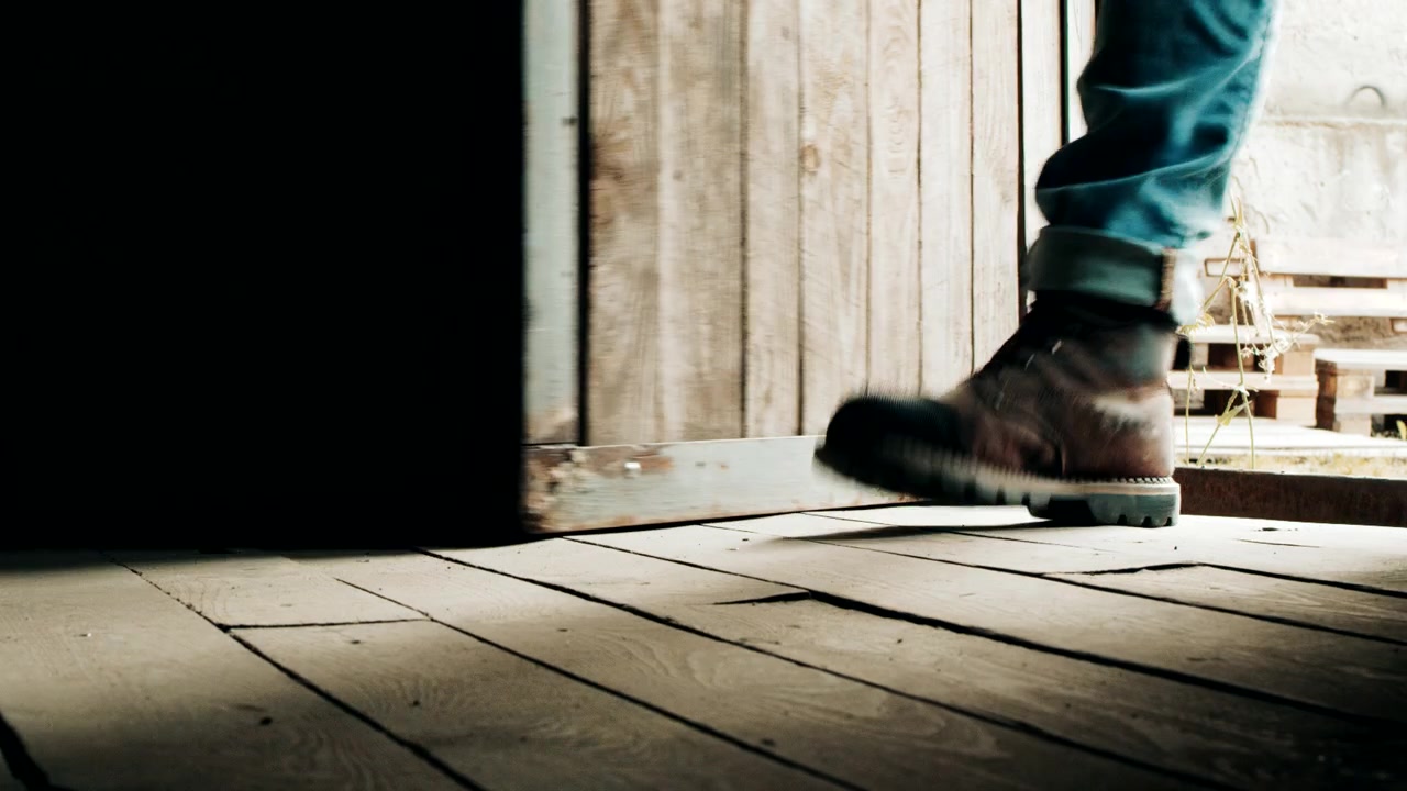 Piedi maschili che entrano. Scarpe da uomo entrano in una casa di legno