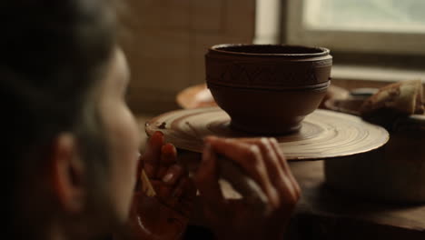 focused woman using tools in pottery