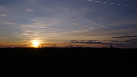 espectacular puesta de sol sobre el campo verde con nubes y rastro de avión