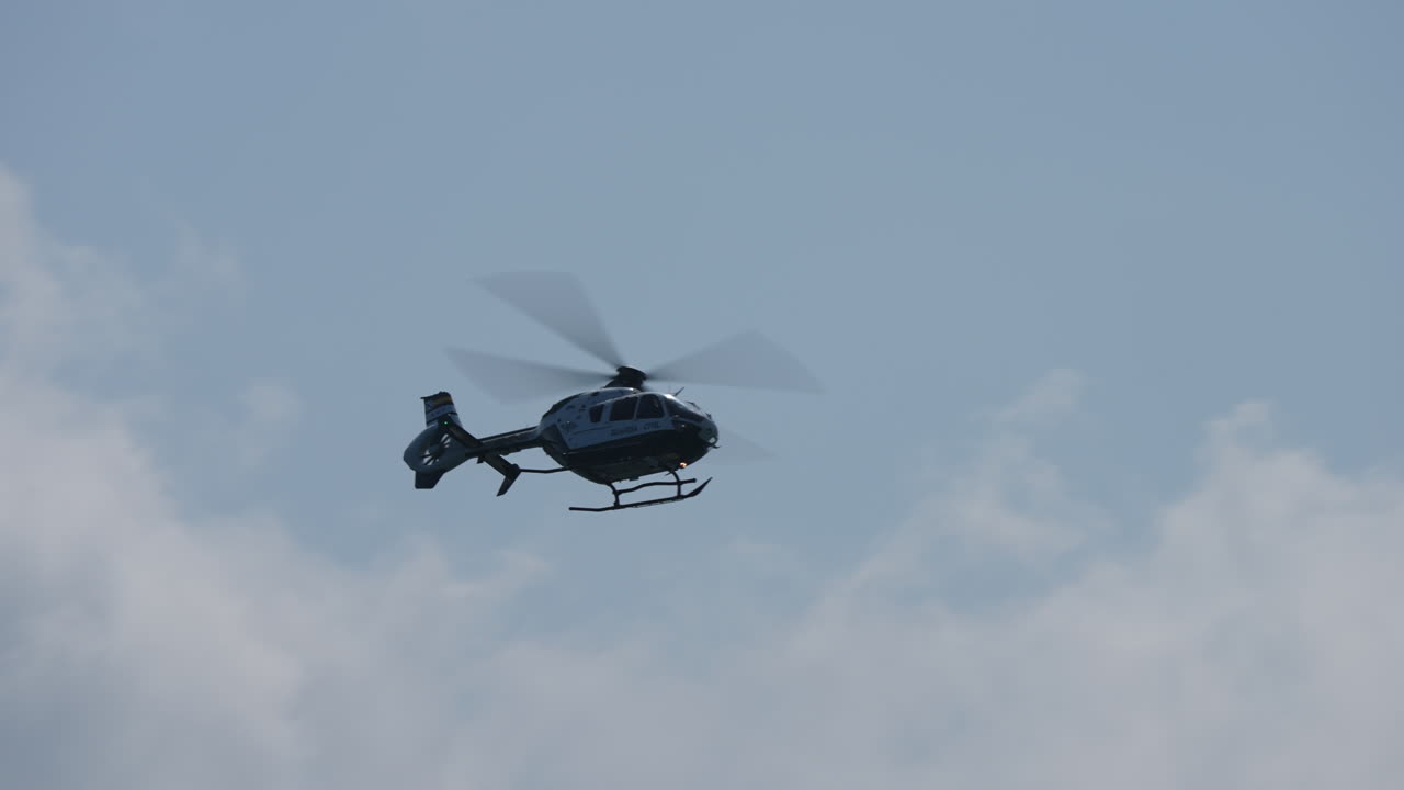 Silhouette of Guardia Civil police helicopter flying across cloudy sky