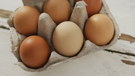 video de primer plano de huevos marrones en cartón de huevos en un fondo rústico
