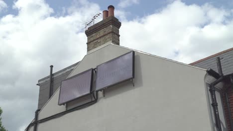 a london residential property with two solar energy panels at the side of it against a backdrop of slow moving clouds