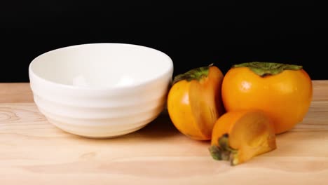 persimmons being thrown into a white bowl