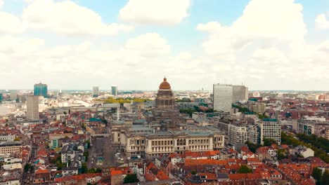 aerial drone video of the court of justice or otherwise known as palace of justice in brussels, belgium, europe during a sunny day with small medieval historic building and cobblestone road around it.