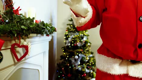 Mid-section-of-santa-claus-placing-gift-box-on-fireplace