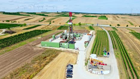 oil rig drilling amongst agricultural fields in austria - aerial drone shot