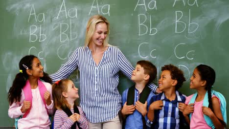 Happy-teacher-standing-with-schoolkid-in-classroom