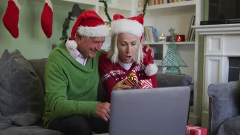 Happy-senior-caucasian-couple-celebrating-christmas-wearing-santa-hats