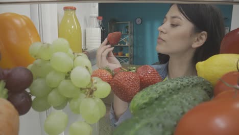 woman looking inside a fridge full of fresh fruits and vegetables