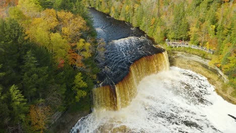 Stationary-aerial,-powerful-river-waterfall-and-viewing-platform-with-people,-wide-shot