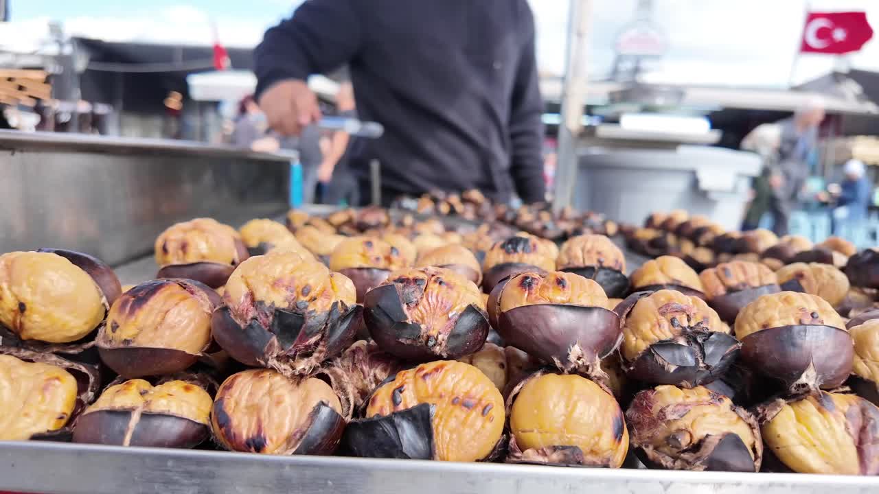 Close-up of Roasted Chestnuts at a Street Food Stall with Vendor