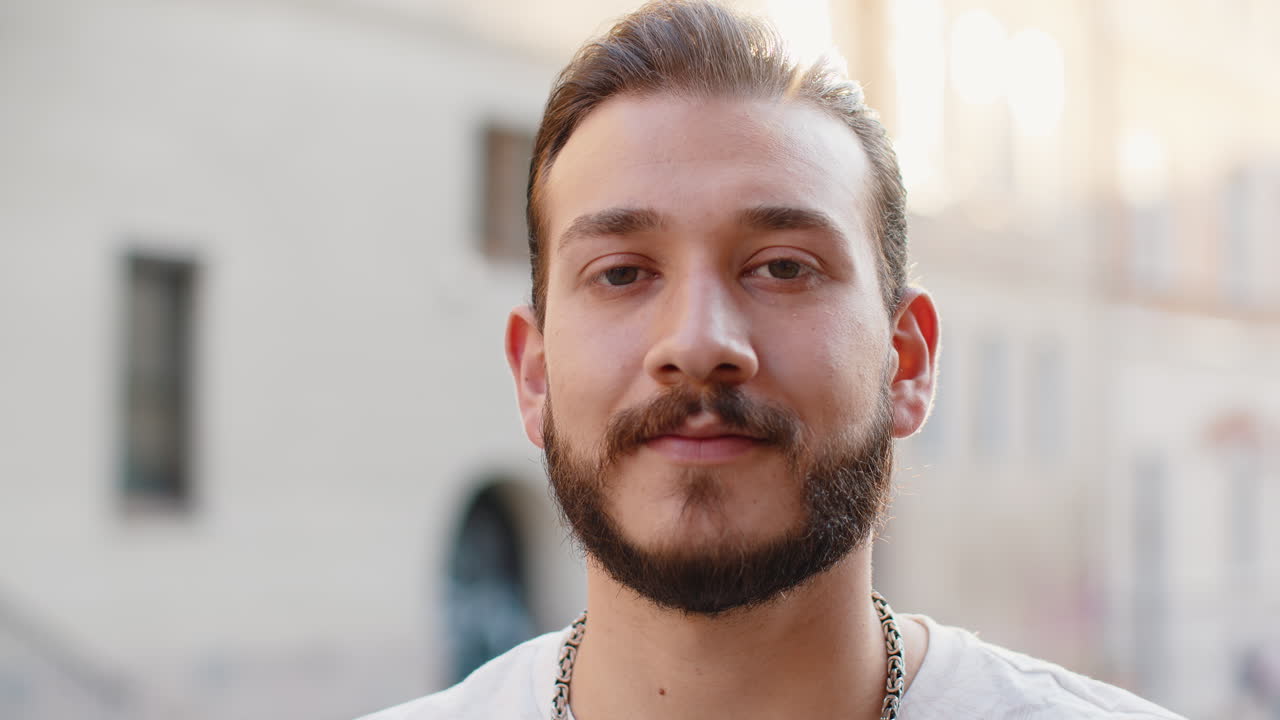 Un giovane felice sorride, guarda lontano, sogna, si riposa, ha buone notizie, si sente soddisfatto per la strada della città.