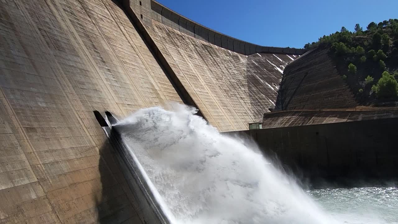 Bottom drain in dam discharging water. Gravity dam discharging water into the river. Panoramic view of the dam and river. Renewable energies. Hydroelectric satation