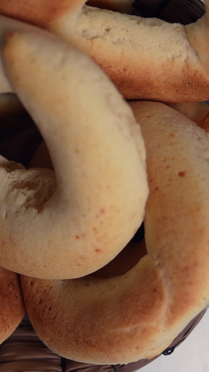 Detailed view of delicious golden pandebono in a basket, shot in vertical video format. The soft texture and warm lighting enhance its appeal, ideal for social media and mobile