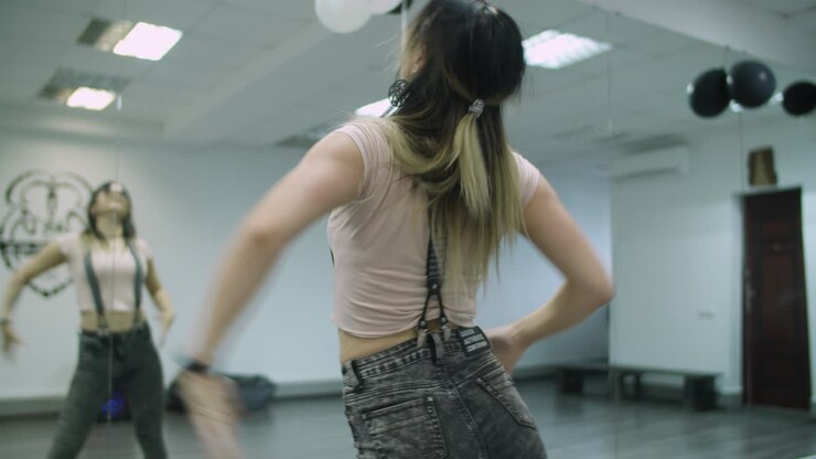 Caucasian female dancer choreographer performing a freestyle dance in dance studio against mirror wall