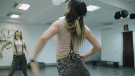 Caucasian-female-dancer-choreographer-performing-a-freestyle-dance-in-dance-studio-against-mirror-wall