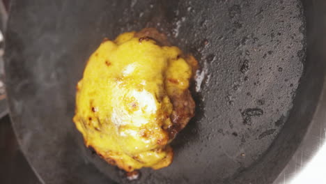 From-Close-up-to-Medium-Shot-of-Cheesy-Melted-Crust-on-Meat-Patty-while-on-Hot-Pan,-Portrait