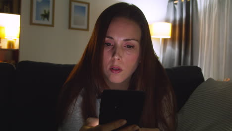 Anxious-Woman-Sitting-On-Sofa-At-Home-At-Night-Looking-At-Mobile-Phone-Concerned-About-Social-Media-Or-Bad-News-4