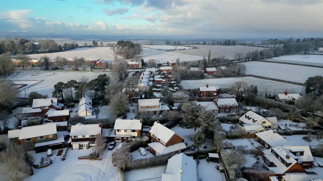 A breathtaking drone shot of an English village, where crisp winter air and fresh snow meet warm morning light.