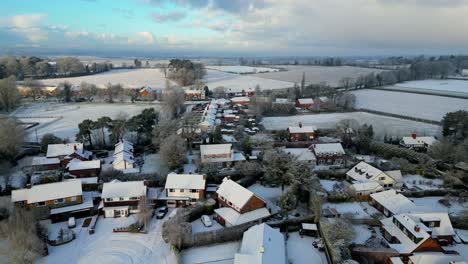 a breathtaking drone shot of an english village, where crisp winter air and fresh snow meet warm morning light.