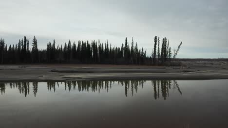 Drone-tracks-tree-line-over-Alaskan-river