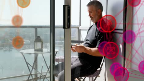 globo de iconos digitales contra un anciano caucásico que usa un teléfono inteligente en el balcón de su casa